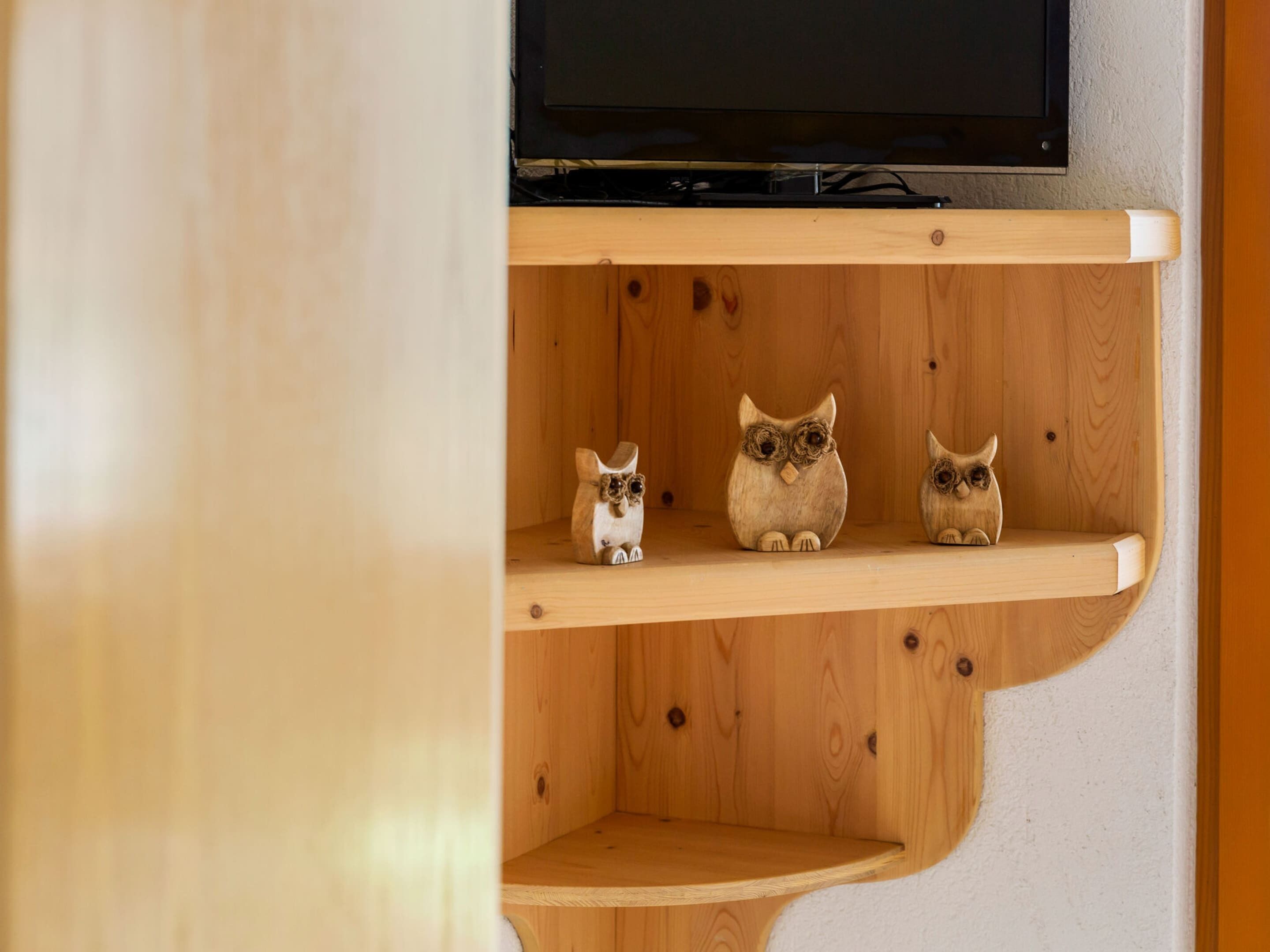 A wooden shelf with three ceramic owl figurines.