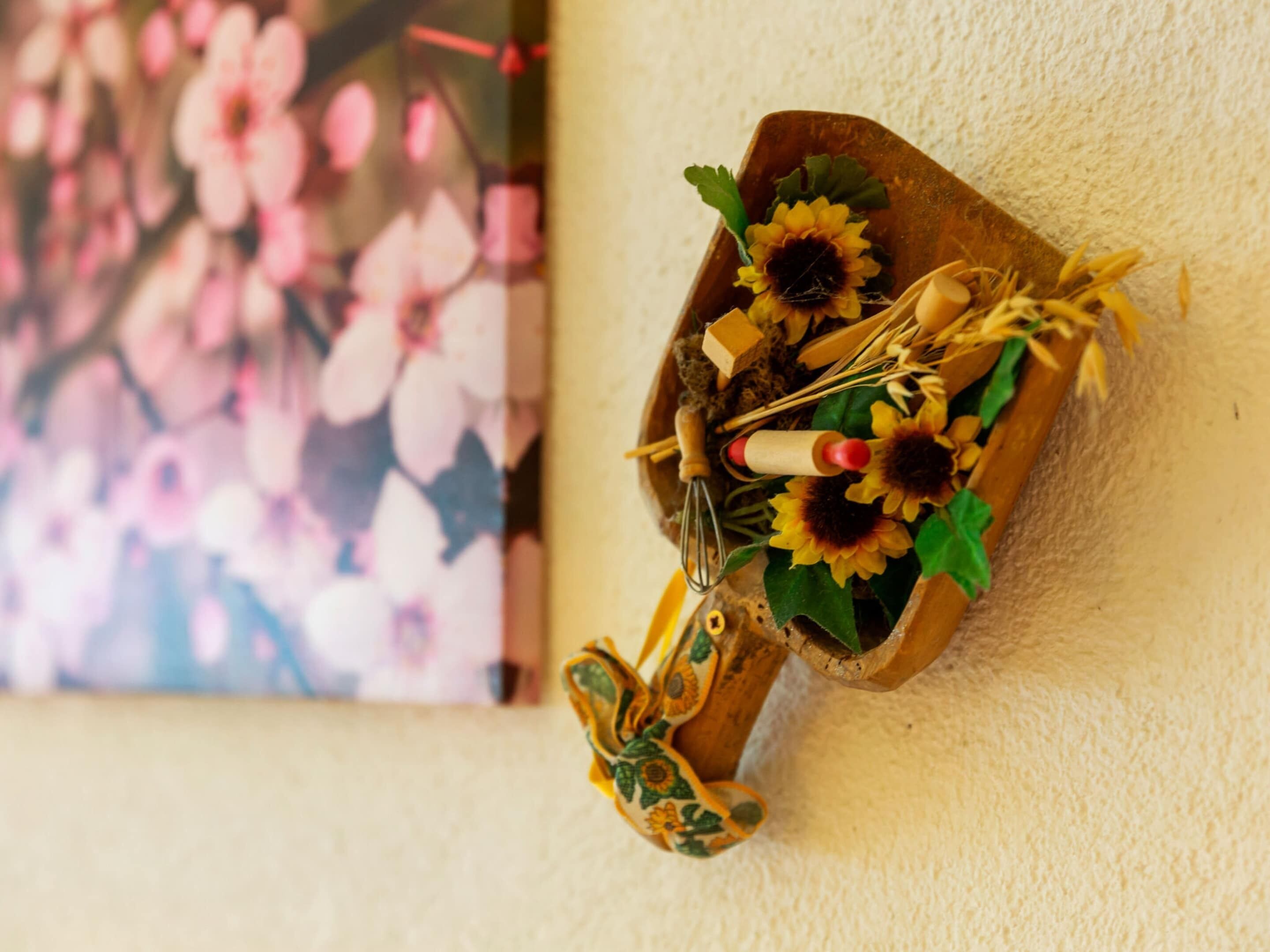 Een houten doos met een rustieke uitstraling, met een zonnebloem, een garde en een kleine houten lepel.
