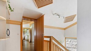 Ein geräumiger Flur mit einer Holztreppe und Blick ins Freie.