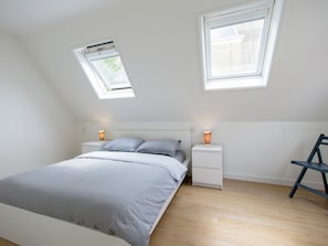 A bedroom with a bed, two bedside tables, a desk, and two windows. - Holiday Home Harlingen Near the Sea (Harlingen)