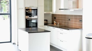 Ett modernt kök med vita skåp, en varmluftsugn och en diskho i rostfritt stål.