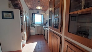 A narrow kitchen with a brick ceiling, wooden cabinets, and a window providing a view of the sea. - Tuscan Hilltop Getaway (Castelnuovo di Val di Cecina)