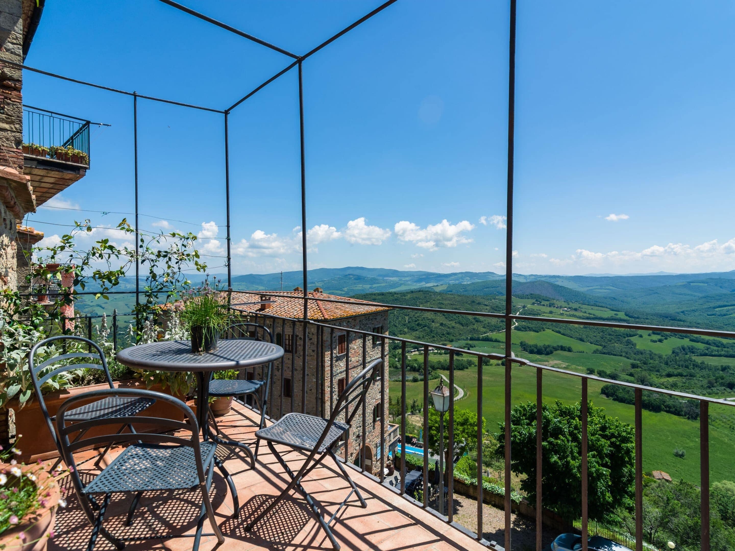 A balcony with a table and chairs, overlooking a scenic landscape.