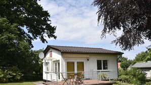 A single-story house with a deck, a satellite dish, and a small garden.