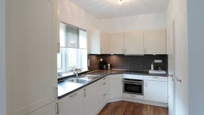 A modern kitchen with white cabinets, a stainless steel sink, a black countertop, and a built-in oven. - Serene Villa in Kstelberg near Lake & Watersports (Medebach)