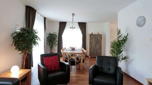 A modern living room with a dining area, featuring a sofa, armchairs, a coffee table, and two potted plants. - Serene Villa in Kstelberg near Lake & Watersports (Medebach)
