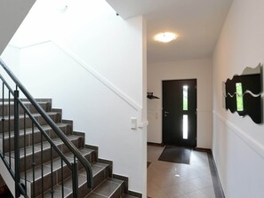 Stairs lead to an entrance with a decorative wall piece and a spacious, well-lit interior.