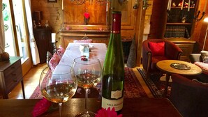 A room with a wooden table, two wine glasses, a bottle of wine, and a red flower. - Chalet Near Bitche With Private Sauna (Bousseviller)