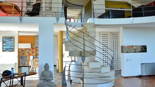 A spacious interior with a spiral staircase, a Buddha statue, and a view of a cityscape through a window. - Charming Ardennes Getaway (Stoumont)