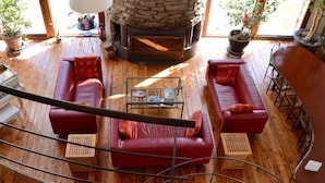 A spacious living room with a stone fireplace, red leather sofas, and wooden flooring. - Charming Ardennes Getaway (Stoumont)