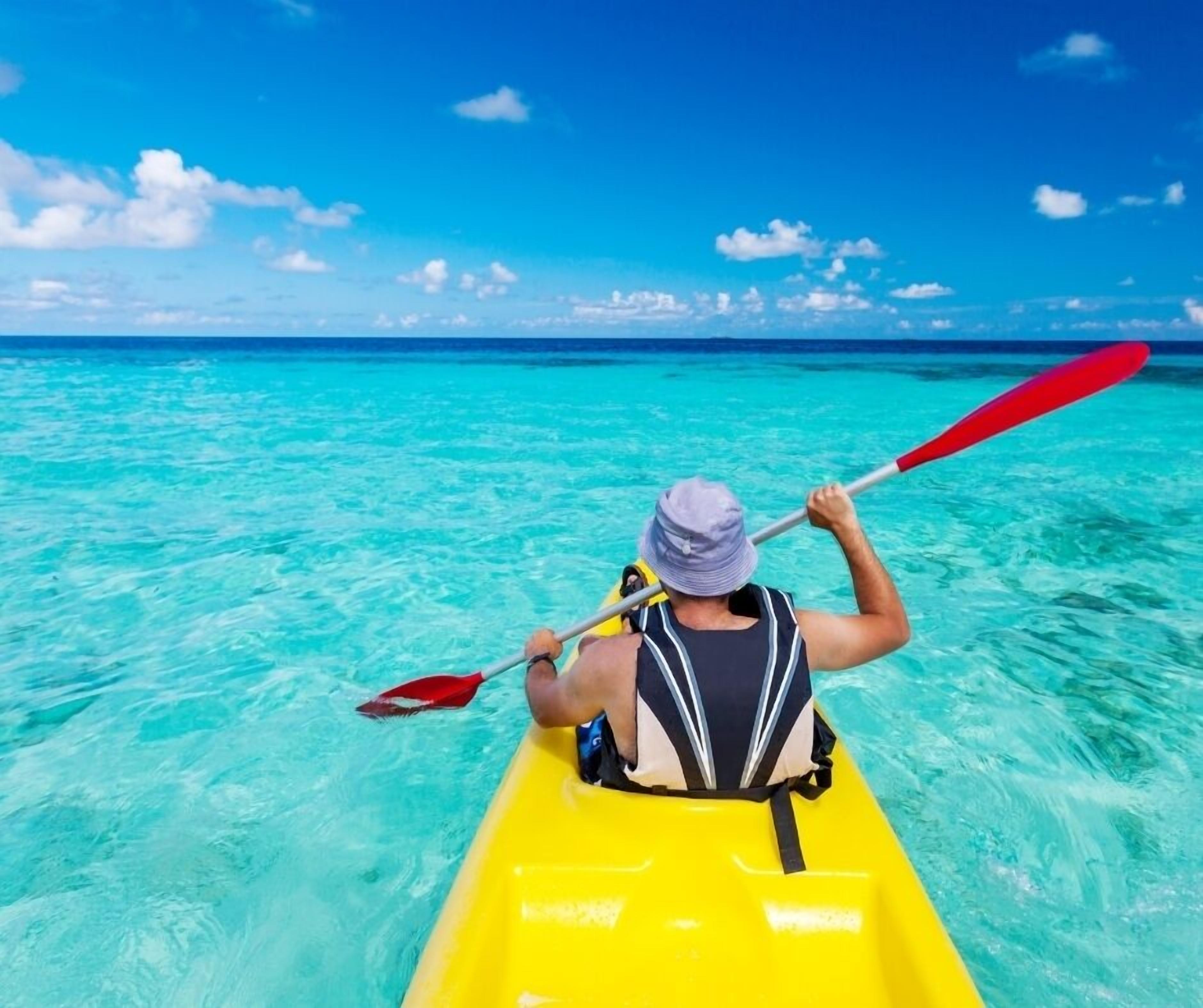 A person kayaking on clear turquoise water.