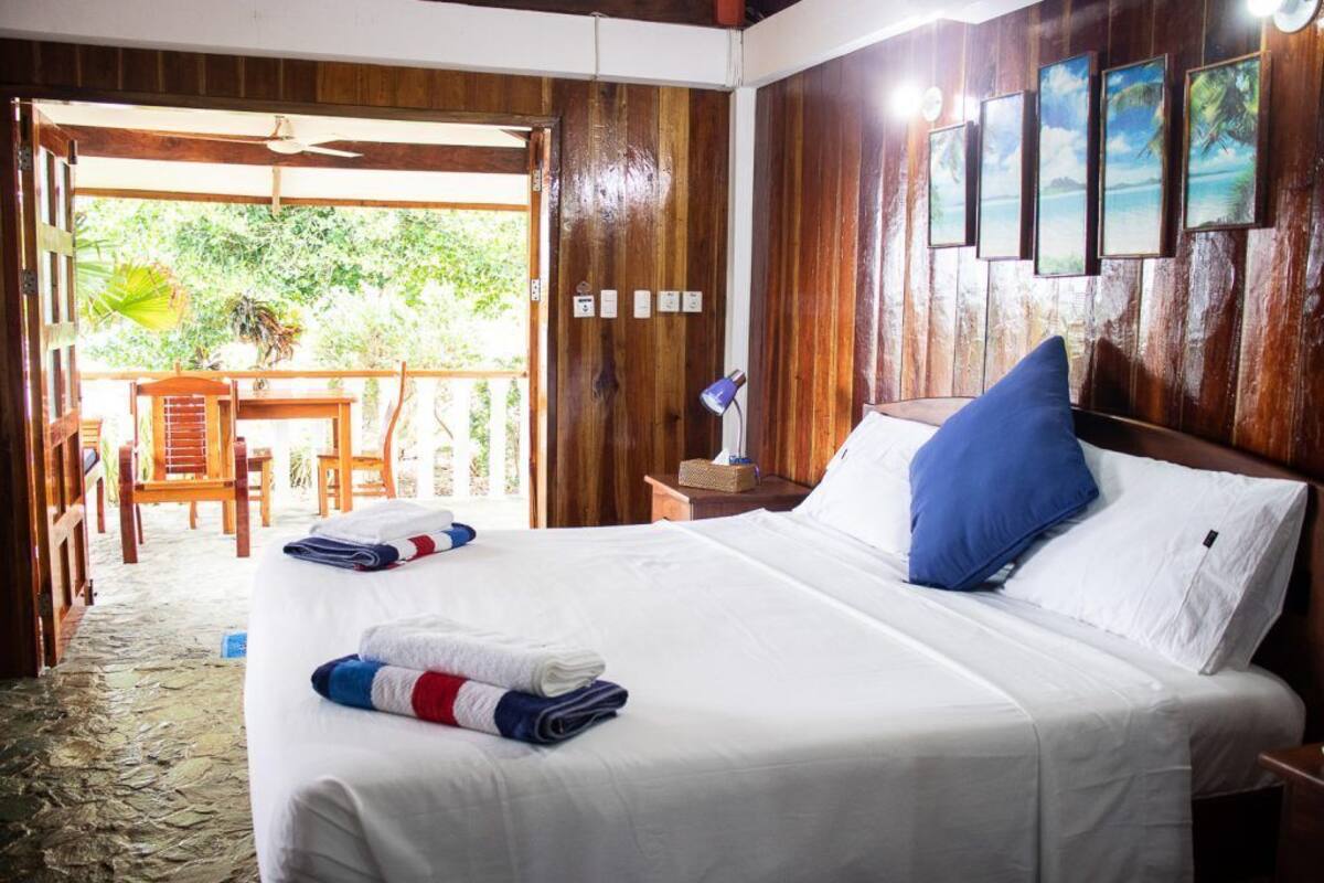 Une chambre d’hôtel avec un grand lit, une tête de lit en bois et une vue sur l’extérieur.