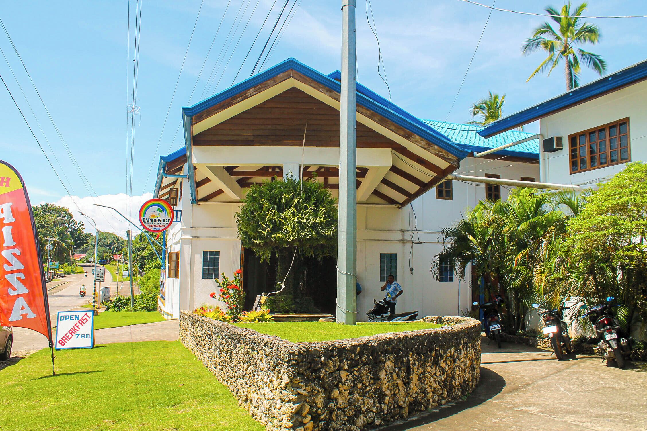 A building with a blue roof and a stone wall in front.