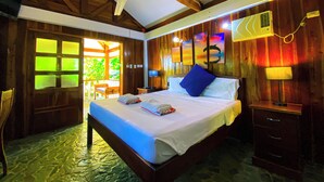 Ein geräumiges Schlafzimmer mit einem großen Bett, einem Deckenventilator und Holzwänden.