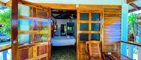 A wooden cabin with a bed, a wooden chair, and a welcome mat.