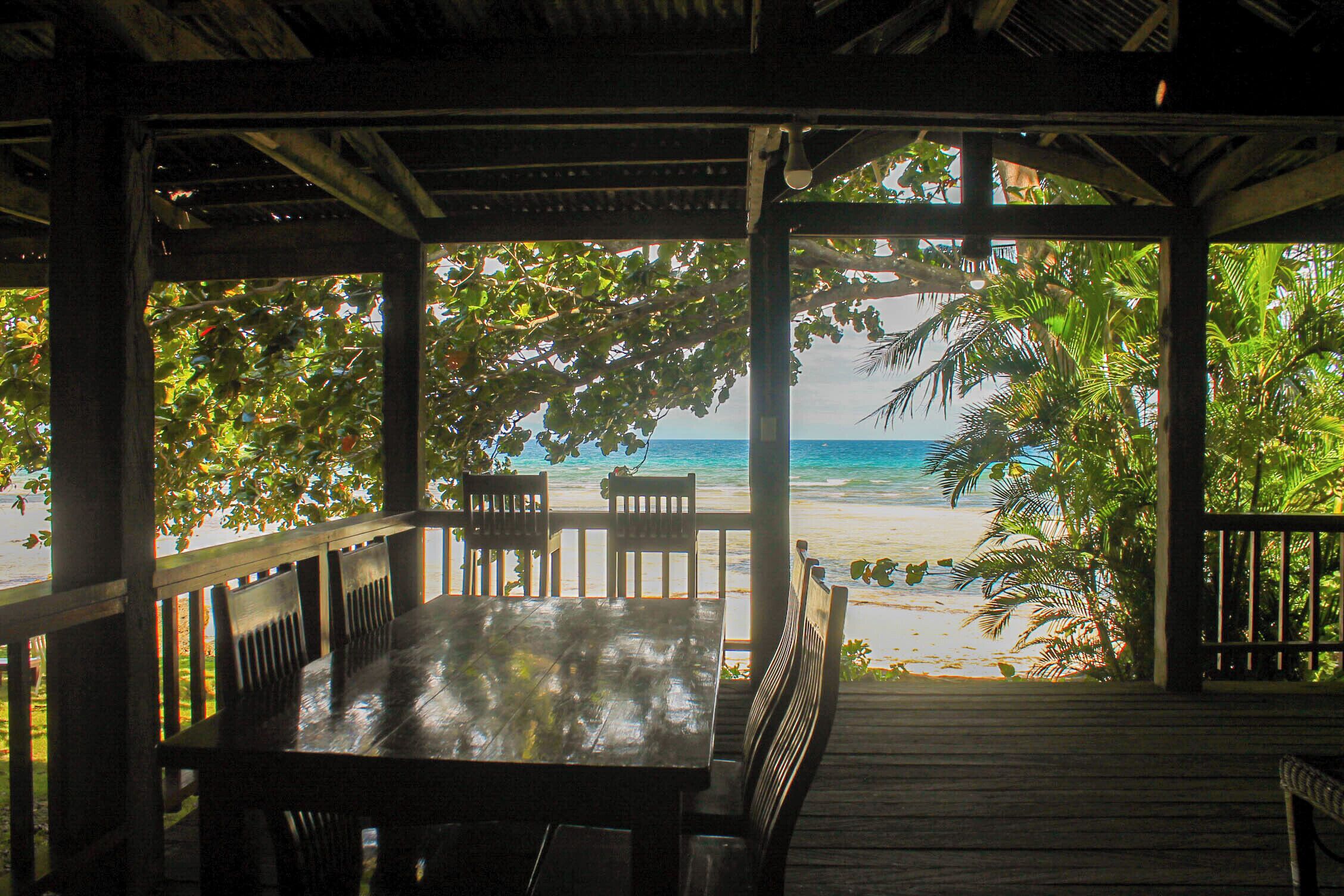 A covered outdoor seating area with a view of the beach and ocean.