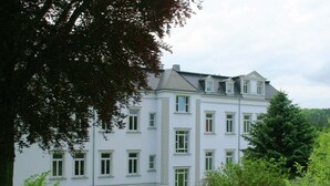 Un immeuble à plusieurs étages, doté d’une façade symétrique, de grandes fenêtres et d’une entrée centrale.