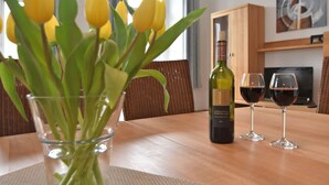 Une table à manger ornée d’un vase de tulipes jaunes, d’une bouteille de vin et de deux verres à vin.