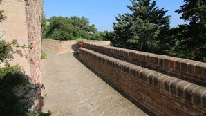 A stone pathway leading to a brick wall with a potted plant and a street lamp. - Apartment in Piticchio With Pool and BBQ (Arcevia)