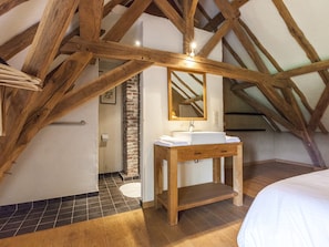 A bedroom with a wooden ceiling, a white sink, and a mirror.