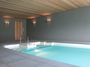An indoor swimming pool with a wooden ceiling, a door, and wall-mounted lights. - Beernem Farmhouse With Pool (Beernem)