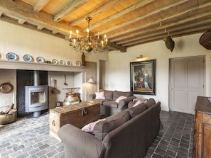 A rustic living room with a fireplace, sofa, wooden beams, and a chandelier. - Beernem Farmhouse With Pool (Beernem)