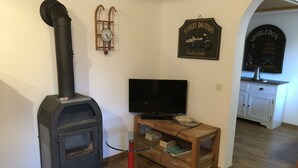 Ein Wohnzimmer mit Kaminofen, Fernseher und Wanduhr.