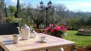 Una mesa de patio con juego de té y una planta en maceta.