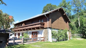 A traditional chalet with a sloped roof, wooden balcony, and stone foundation. - Holiday Home With Balcony (Bruck an der Grossglocknerstrasse)