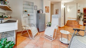 A modern kitchen with white appliances, a glass shelf with decorative items, and a white chair. - Apartment in Schleiden With Sauna and Nature (Hellenthal)