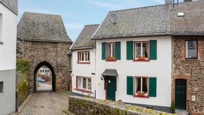 A narrow cobblestone street with historic stone buildings, a stone archway, and a traditional European architectural style. - Apartment in Schleiden With Sauna and Nature (Hellenthal)