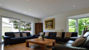 A spacious living room with two black leather sofas, a wooden coffee table, and large windows offering a view of the outdoors. - Spacious Villa in Zingem With Garden (Vresse-sur-Semois)