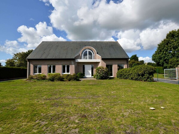 A two-story house with a brick facade, a pitched roof, and a front entrance with a semi-circular arch.