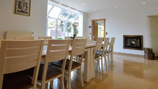 A dining area with a large table and chairs, a radiator, a framed picture on the wall, and a window with a view of greenery. - Spacious Villa in Zingem With Garden (Vresse-sur-Semois)