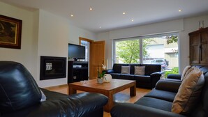 A modern living room with a black leather sofa, a wooden coffee table, and a TV on a stand. - Spacious Villa in Zingem With Garden (Vresse-sur-Semois)