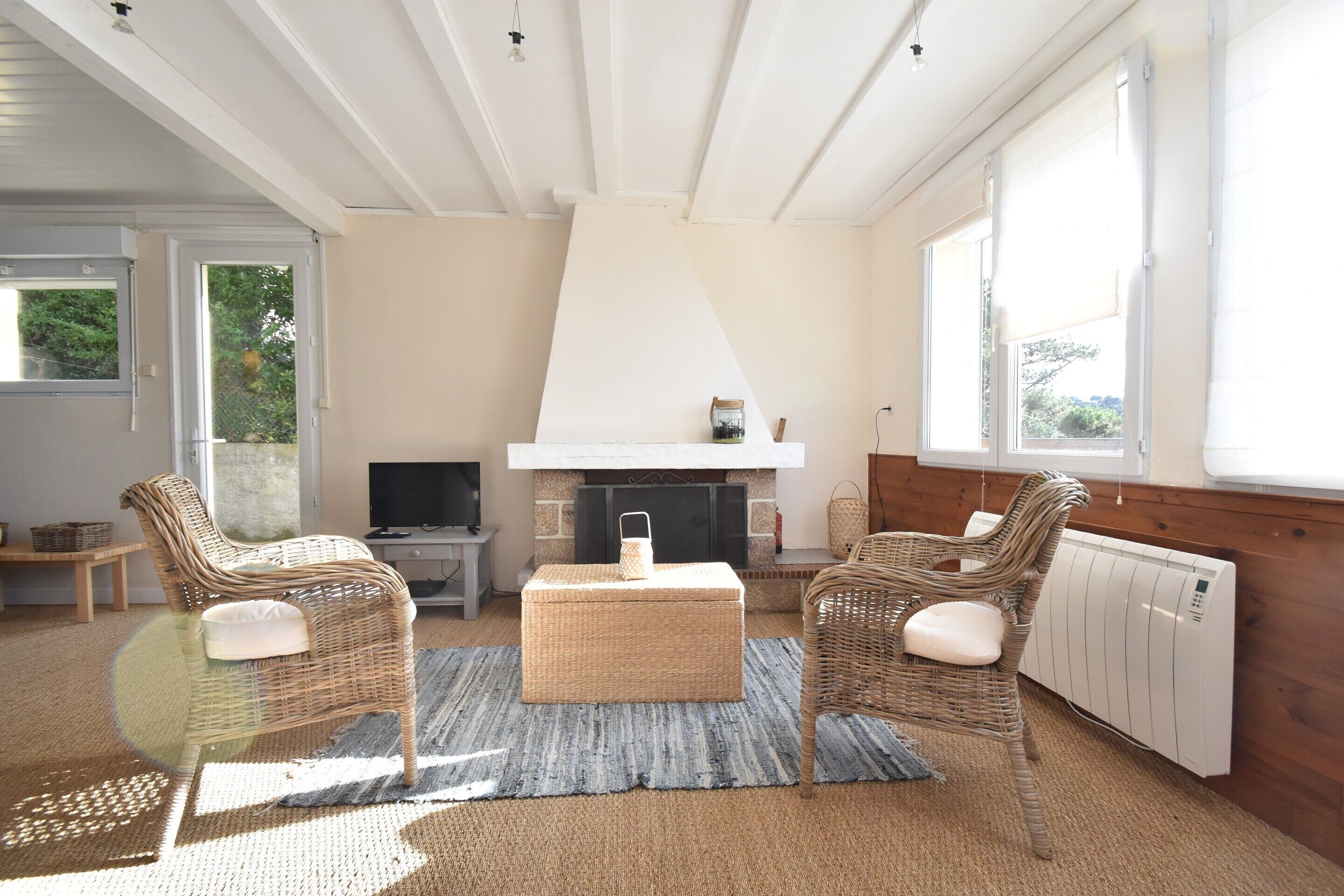 A room with wicker furniture, a fireplace, a television, and a view of the outdoors.
