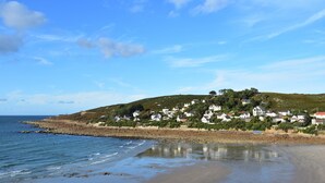 A coastal village with houses on a hillside, a beach, and calm sea. - Sea View Stay in Fermanville (Fermanville)