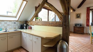Une cuisine avec un plafond orné de poutres en bois, un évier, des placards et une fenêtre.
