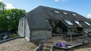 Un bâtiment en pierre doté d’un toit en pente et de lucarnes, une terrasse avec des sièges extérieurs, et un sol en gravier.