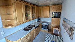 Une cuisine compacte avec des meubles en bois, un four encastré et un four à micro-ondes.