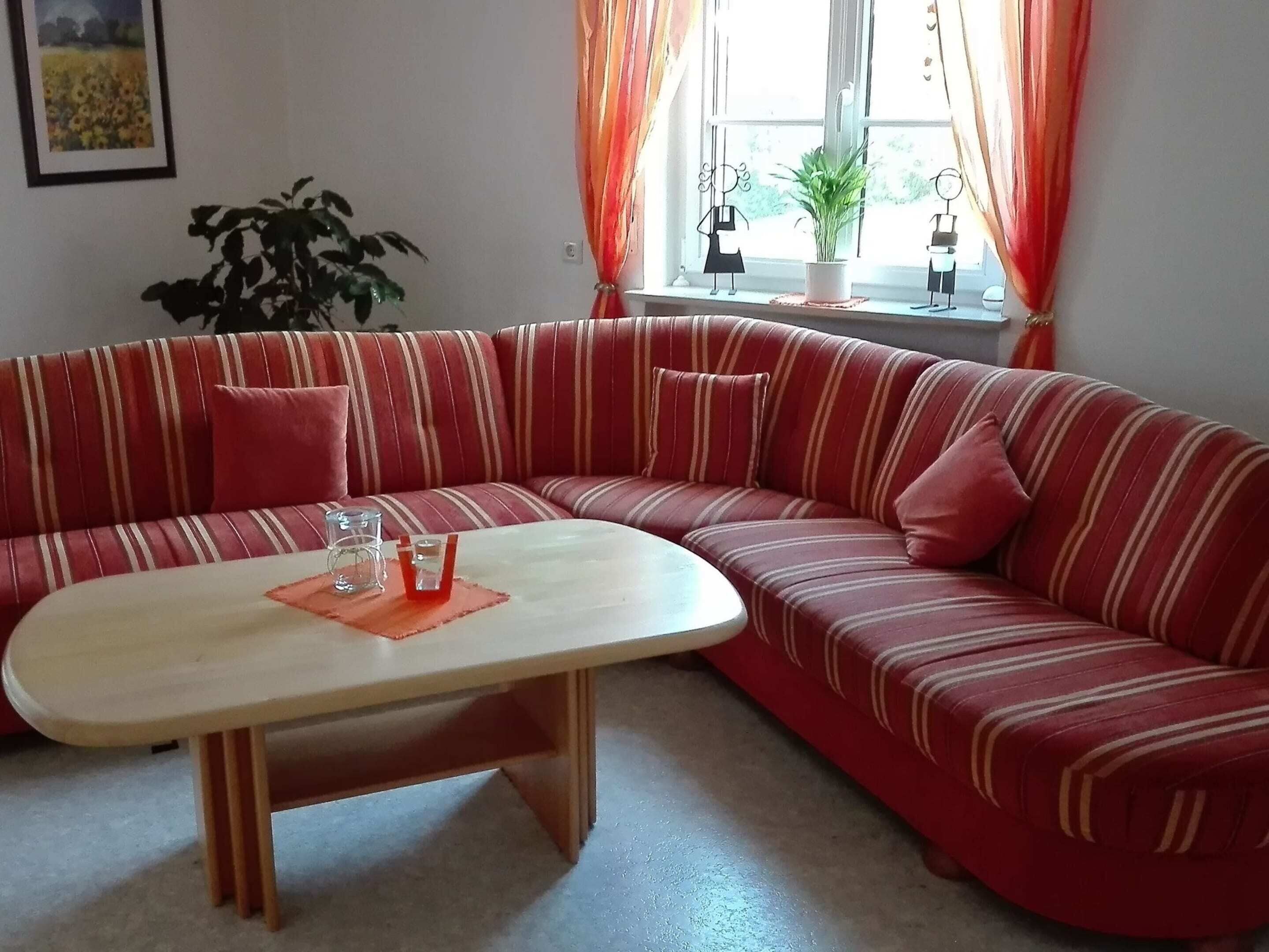 A red-striped sofa with a matching armchair, a small table, and a potted plant.