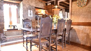 A rustic dining area with wooden chairs and a table, stone walls, and a hanging light fixture. - Gouvets Family Retreat (Gouvets)