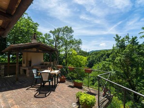 A patio with a table and chairs, surrounded by potted plants and overlooking a lush green landscape. - Belvilla by OYO Lupo (Cagli)