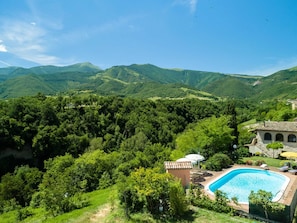 A pool surrounded by lush greenery and hills. - Belvilla by OYO Lupo (Cagli)