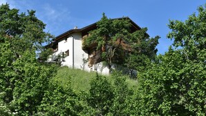 A two-story building with a sloped roof, surrounded by lush greenery. - Cozy Stay Near Aletsch (Grengiols)