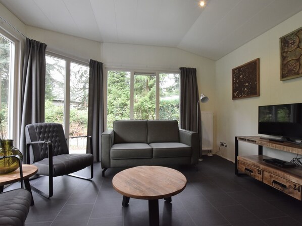 A modern living room with a grey sofa, a black armchair, and a round wooden coffee table. - Stylish Stay in Vorden Woods (Vorden)