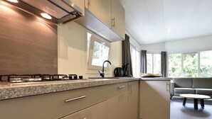 Une cuisine moderne équipée d’une cuisinière à gaz, d’un four encastré et d’une fenêtre donnant sur un espace verdoyant.
