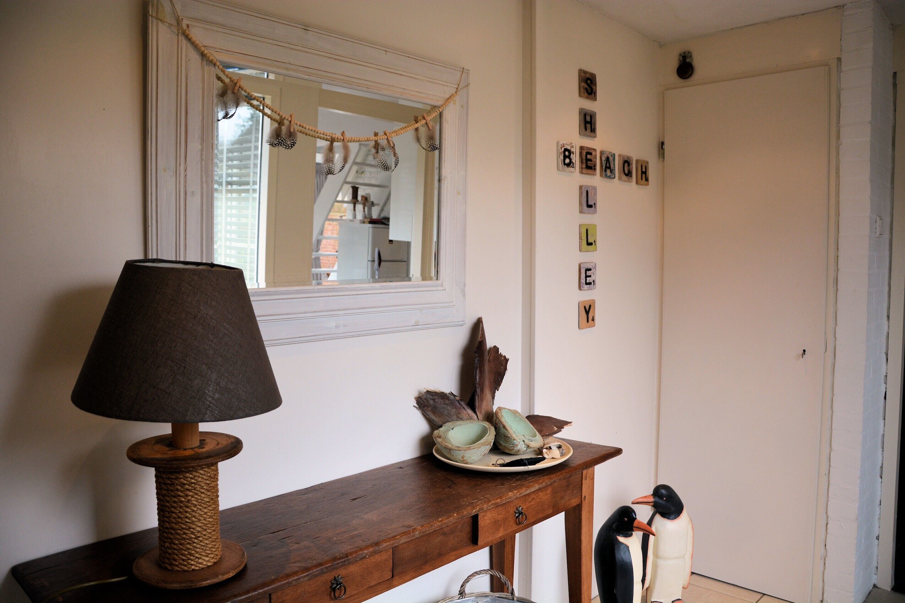 A wooden console table with a lamp, decorative items, and a penguin figurine.