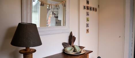 A wooden console table with a lamp, decorative items, and a penguin figurine.