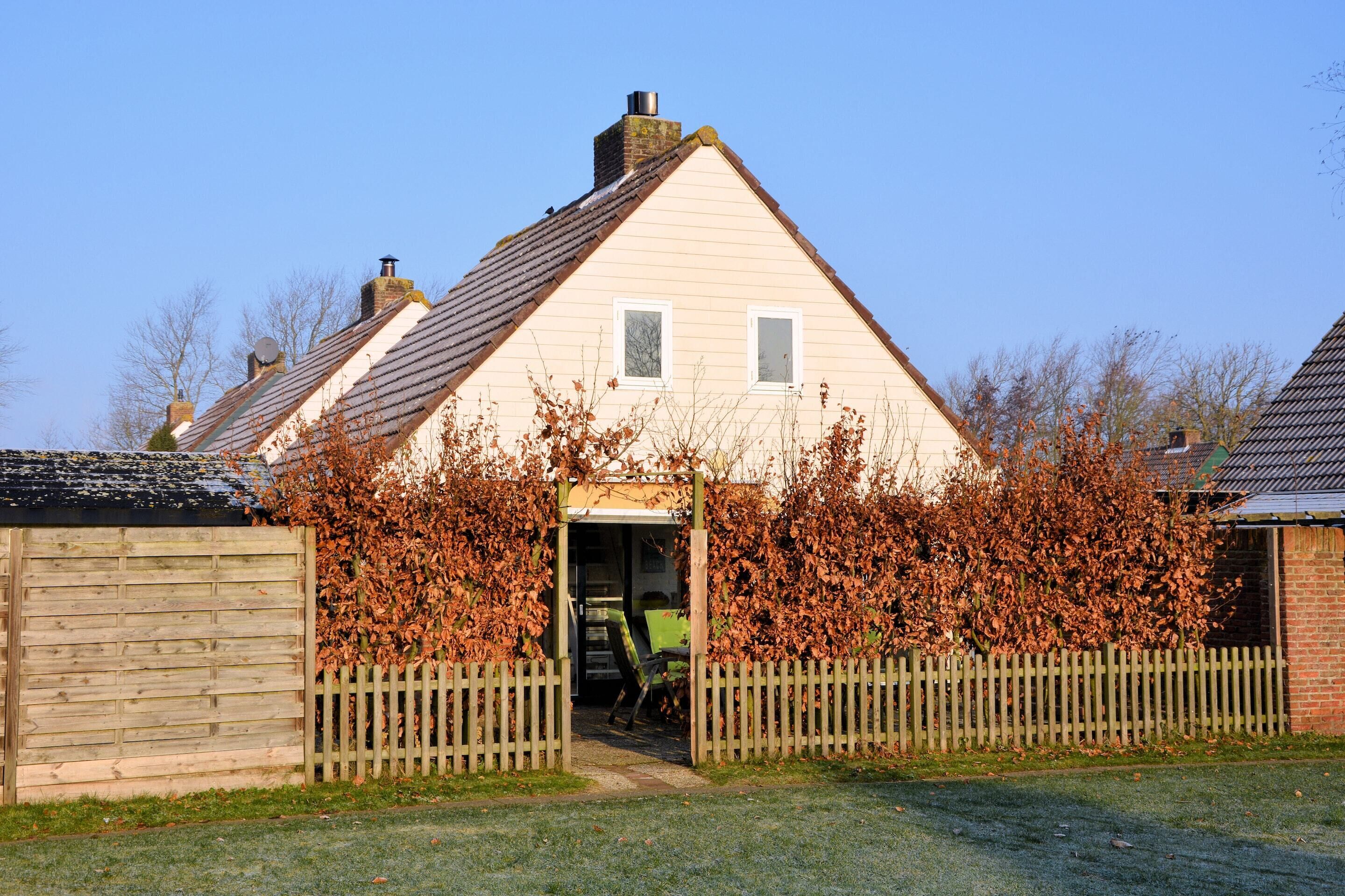 A house with a pitched roof, a wooden fence, and a garden area.